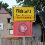 Dorfeingangsschild von Pödelwitz mit Protestfahne