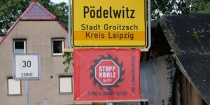 Dorfeingangsschild von Pödelwitz mit Protestfahne