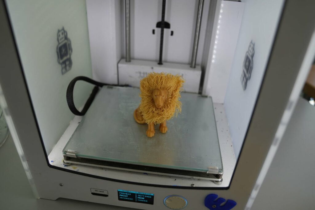 Gedruckte gold-gelbe Löwenfigur mit Mähne in einem 3D-Drucker
